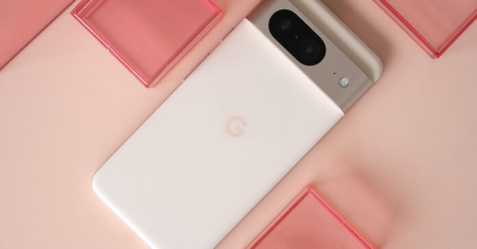 Google Pixel 8 with rear panel facing up in pink on a light pink background with red plastic cubes