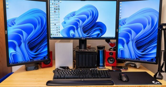 Three monitors sit atop a Fully Jarvis Bamboo Standing Desk.