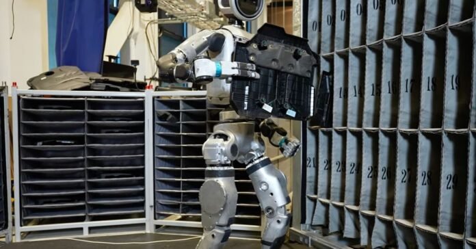 Boston Dynamics all-electric Atlas robot is seen moving parts between containers.